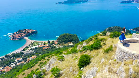 Young Couple Admire a Panorama of the Sea and Island of Sveti Stefan in Montenegro alt