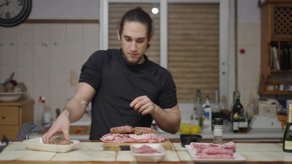 Young Caucasian Man Looks Happy While Taking Burgers Out of the Tray for Preparation in Slow Motion alt