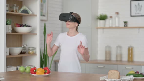 Modern Young Woman Using VR Set While Standing in Kitchen alt