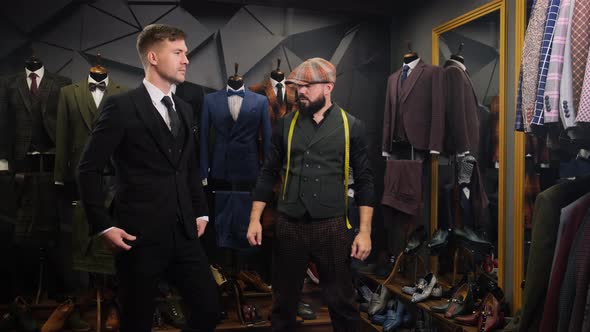 Tailor Dresses a Handsome Young Man in a Quality Handmade Suit in an Atelier. Creative Adult Stylist alt