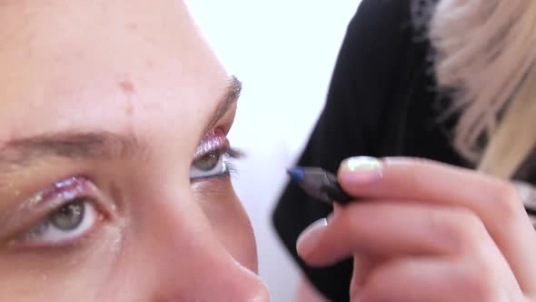 Professional Stylist Makeup Artist Applies a Turquoise Eyeliner Pencil While Making a Bright Evening alt