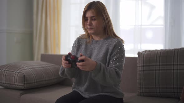 Portrait Plus Size Girl Playing Video Game Sitting at Sofa in Home alt