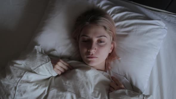 Depressed young woman lying on bed, female insomnia at night