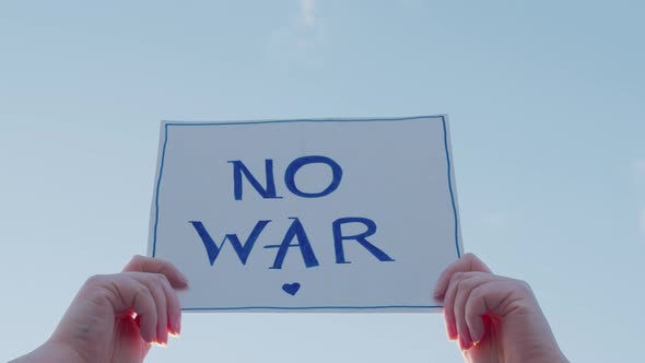 Closeup of a Cardboard Sign with the Inscription No War on the Blue Sky