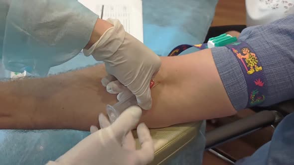 a nurse inserts a needle into a man's vein so that the person can donate blood. Blood donation.