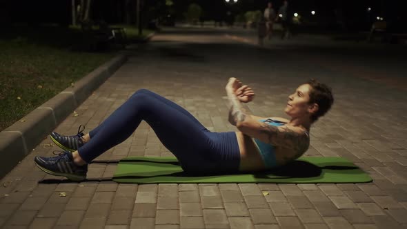 Young Girl Doing Exercise on the Abdominal Muscles in the Evening Park alt
