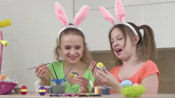 Two Girls Decorate Easter Eggs with a Brush and Help Each Other Talk and Laugh