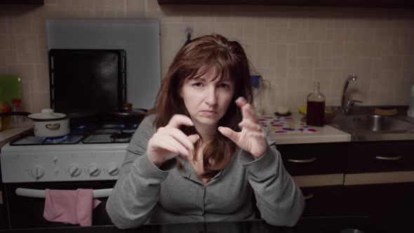 Sad Woman Sits in the Kitchen and Tears a Letter Into Small Pieces in the Evening alt