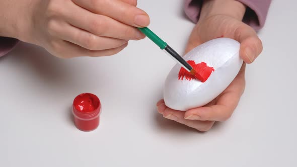 Hand Paints a Foam Plastic Heart in Red