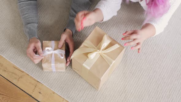 Family Man and Woman Lying on Floor Unpacking Gift Boxes in Christmas at Home.