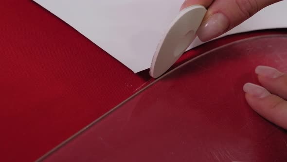 Woman Tailor Hands Chalked a Paper Pattern on Red Cotton Fabric alt