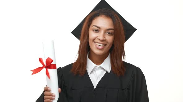 Happy Smiling African American Graduate Student in Black Academic Dress Showing Her Diploma and Ok alt
