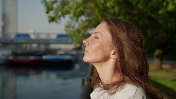 Closeup of a Brunette's Face on the City Embankment on a Sunny Day alt