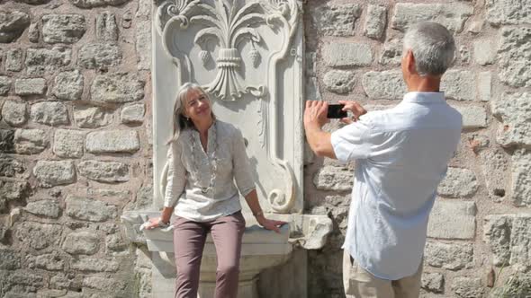 Senior woman posing for male taking picture in front of fountain, Istanbul, Turkey alt