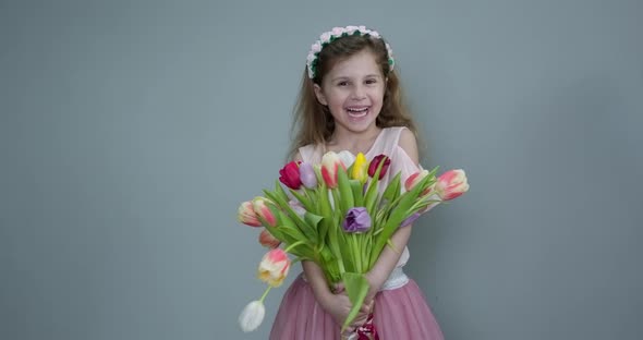 Cute Small Kid Child Holding Tulips and Smiling to the Camera alt