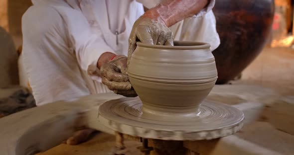 Skilled Hands of Potter Shaping the Clay on Potter Wheel and Sculpting Clay Pot Jar. Shilpagram alt