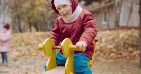 Small Cute Child Rides on a Swing in the Yard on a Walk with His Parents alt