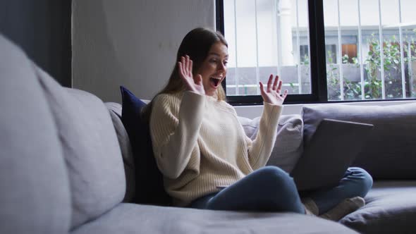Woman having a video chat on her laptop at home alt