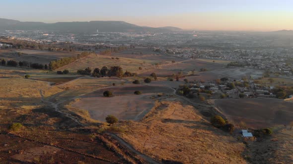 Expansive aerial pan down of the countryside in Colima, Mexico at sunset. alt