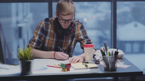 Young Male Designer in Shirt, Glasses, with Beard Draws Using Marker