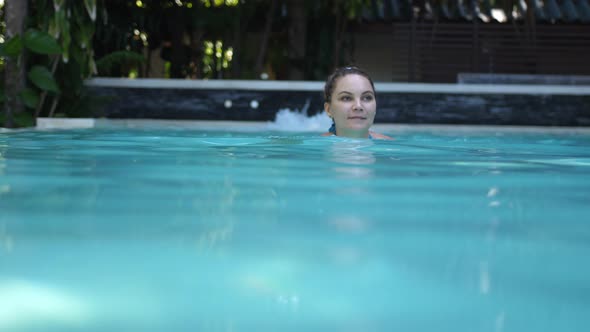 Beautiful Young Woman Swimming in a Pool at a Luxury Spa in Tropics