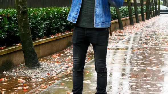 Man holding umbrella and talking on mobile phone alt