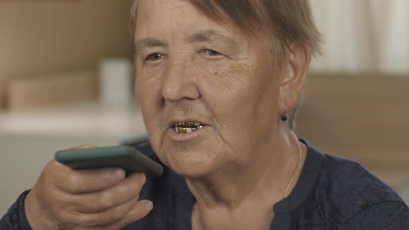 Recording voice message. Senior woman Talking on the mobile phone at home. alt