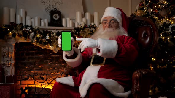 Modern Smiling Santa Claus Points Finger at Smartphone Green Screen Markers alt