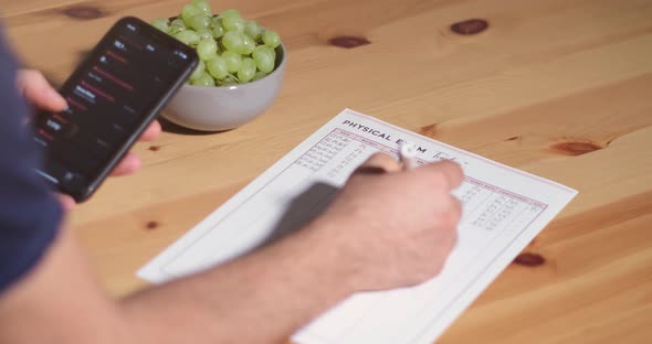 A young man writes weight, BMI, blood pressure, heart rate, and cholesterol