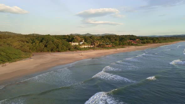 Drone approaching a beachfront hotel at playa grande near Tamarindo, Costa Rica. Few people walk alo alt