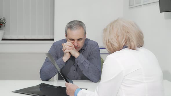 Mature Man Listening Attentively To His Doctor at Medical Appointment