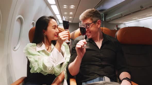 Couple in love holding champagne glasses and cheers while traveling on airplane