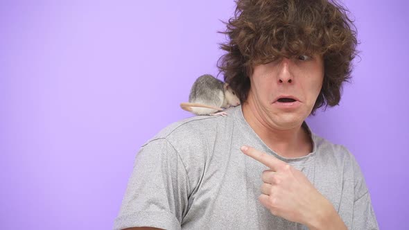 Closeup of a Frightened Young Man with a Pet Rat on an Isolated Purple Studio Background alt