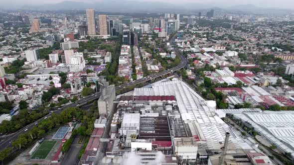 backwards drone shot of beer factory and residential zone at mexico city in the morning alt