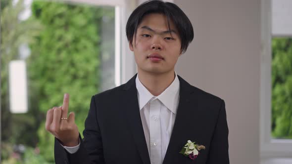 Portrait of Confident Asian Groom in Elegant Suit Showing Finger with Wedding Ring Looking at Camera alt