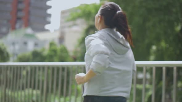 Beautiful young Asian woman runner training in summer park.