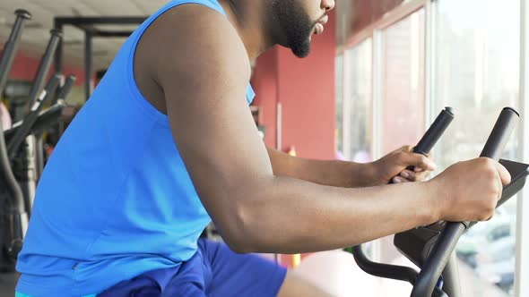 Motivated Man Riding a Stationary Bike, Shaping Up His Body in the Gym alt