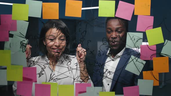 AfricanAmerican Businessman and Businesswoman Celebrate Successful Startup Strategy on Glass Board alt