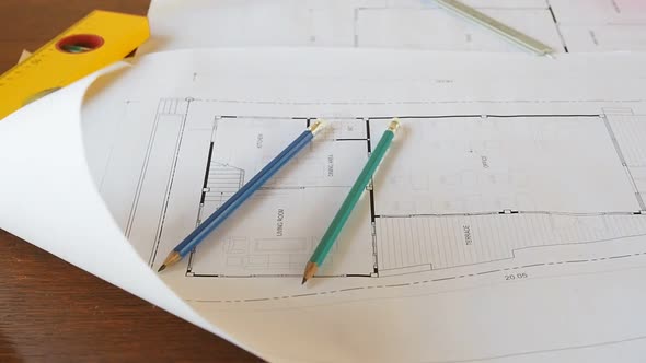 Level tool, pencils and ruler on architectural blueprints.