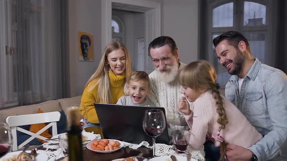 Family Watching Beautiful Photos on Computer which Showing them Respected Senior Grandpa alt
