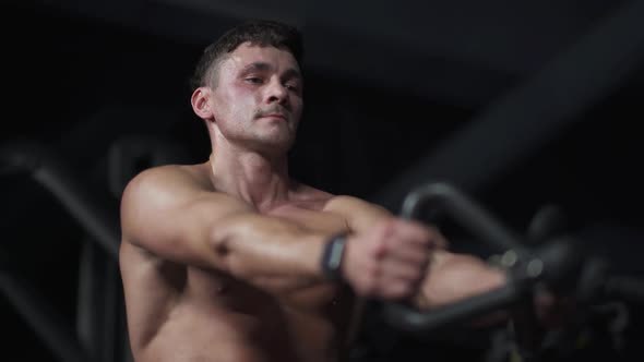 Man in the Gym Lifting Blocks on Rowing Machine Training on Block Device and Gym Equipment Night alt