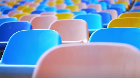 Multi-colored chairs in the stadium. Rows of empty plastic seats in the arena. alt