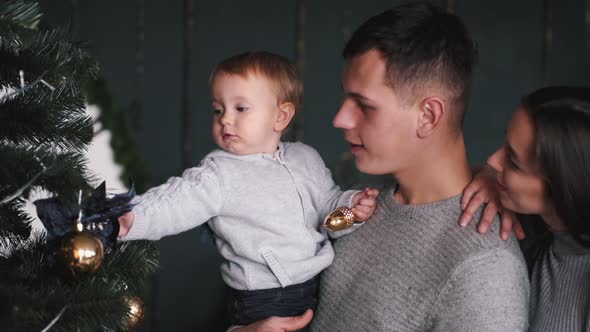 Parents with Little Son Looking at Cristmas Tree at Home alt