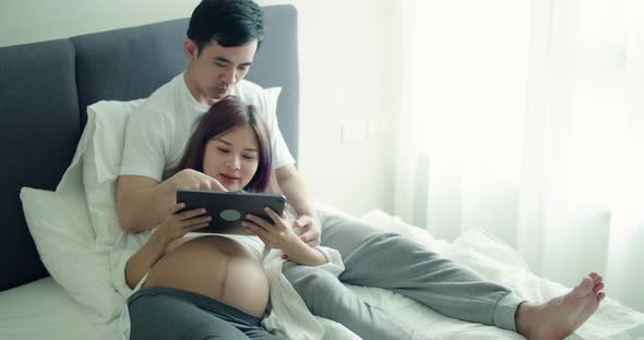 Caucasian husband with a pregnant wife using tablet.