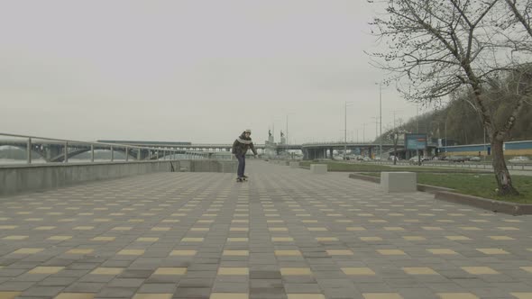 Teenage Boy Riding Skateboard Down Sidewalk in City alt