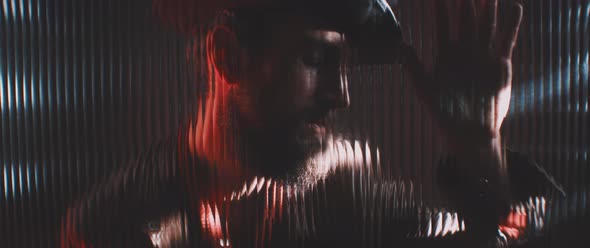 Man in shutter lights looking through clear panel holding hand up alt