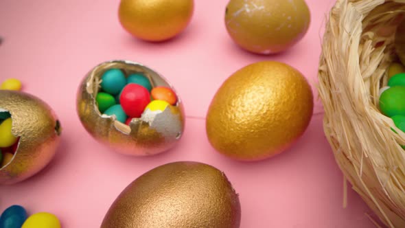 Golden Eggs with Scattered Sweets for Easter on Pink Background