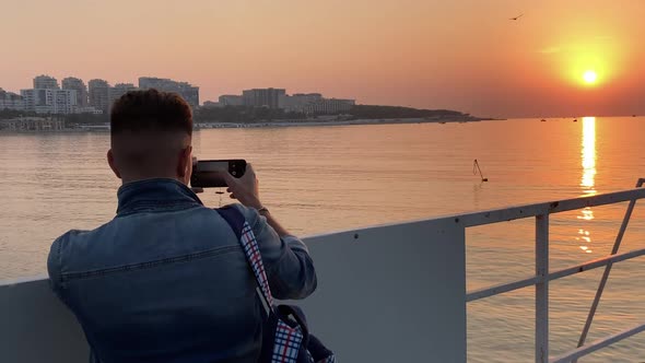 Man Taking Photo Phone Reflection Sunset on Ocean