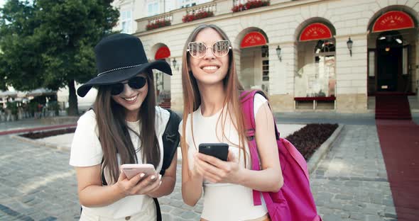 Two Tourist Girls Taking Photo on Smartphones