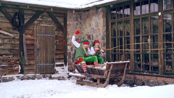 Christmas elves ride wooden sledges. New Year is coming. Christmas eve ...